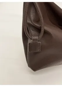 Detail of dark brown leather tote featuring woven lanyard and debossed PAN TOR leather tag