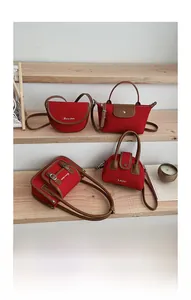 Collection of red nylon crossbody bags with leather trim displayed on wooden steps