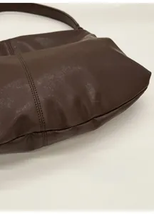 Close-up of brown leather tote bag showing fine grain texture and double stitching detail
