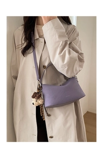 Dettaglio borsa baguette in pelle viola con ciondolo a cucciolo e foulard