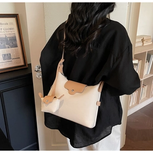 Detail of cream underarm bag and matching mini pouch with contrast brown leather trim