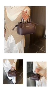 Detail of dark brown litchi pattern leather handbag with fashion text and drawstring side