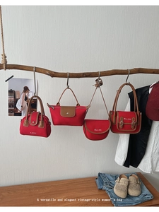 Detail showing various red canvas handbag styles hanging on natural wood branches