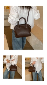 Detail view of dark brown leather Boston bag with adjustable strap and dual handles