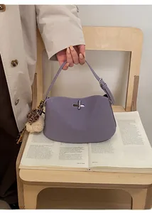 Dettaglio della borsa baguette in pelle lavanda con chiusura a scatto e ciondolo orso