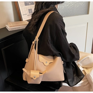Gedetailleerd achteraanzicht van een beige shopper met golvende flap en mini-tasaccessoire