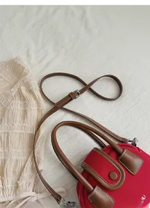 Detail of red canvas small handbag with brown leather straps and precise contrast stitching