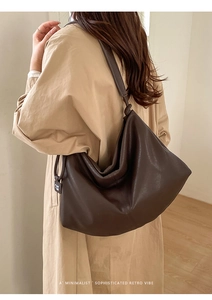 Detail of the soft dark coffee leather texture and branded tag on the tote bag