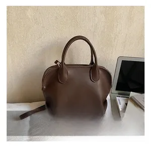 Detail showing deep brown faux leather texture and dual handles of a Boston shell bag
