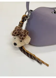 Dettaglio di un ciondolo a forma di orsetto con fiocco leopardato su borsa viola