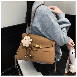 Detailed side view of a caramel lychee leather Kelly-style bag with a plush star charm