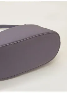 Dettaglio della base della borsa in pelle viola che mostra cuciture e trama fine