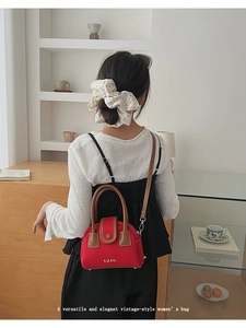 Rear view of model wearing a vintage red leather crossbody bag with top handle and strap