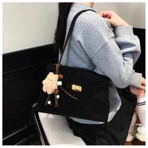 Detail view of black matte underarm tote bag with golden metal buckle and bear charm