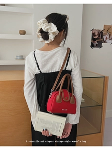 Detail of red vintage women's bag with LIUUU logo, brown leather strap, and carry handle