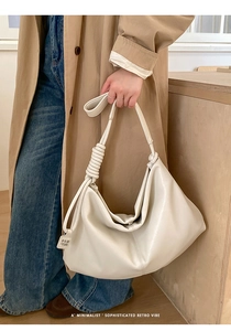 Detail of cream leather tote bag featuring unique knot strap and minimalist hobo design