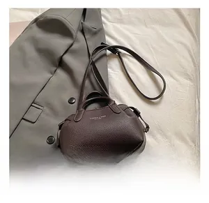 Detail of dark brown lychee grain leather tote bag with silver hardware and shoulder strap