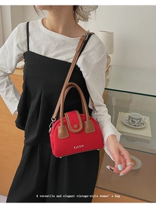 Detail of red vintage crossbody bag with brown handles in a lifestyle coffee shop setting