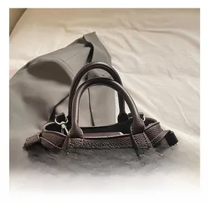 Detail of dark coffee lychee texture leather handbag with drawstring and round handle