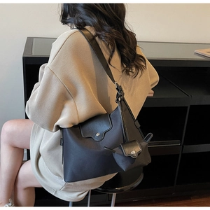 Close-up of black casual shoulder bag with detachable mini coin purse and wide strap