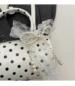 Detail of polka dot handbag featuring pearl bow decoration and white lace texture
