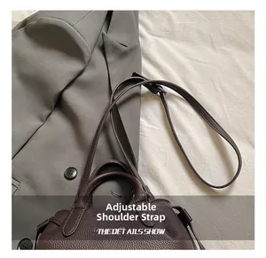 Detail of adjustable shoulder strap and textured leather handle on dark brown tote bag