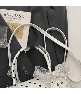 Polka dot Boston bag with pearl bow and lace detail on a grey blazer background