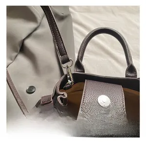 Macro detail of dark brown litchi grain leather tote bag with metallic lobster clasp