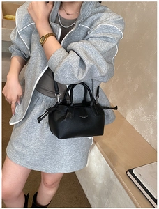 Detail of black pebbled leather tote bag with drawstrings shown on a model