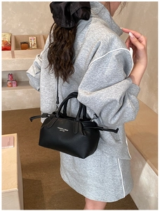 Detail of black lychee grain leather tote bag with white fashion text and shoulder strap