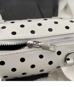 Detailed macro view of the smooth metal hardware zipper on a polka dot cylinder bag
