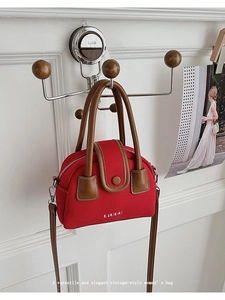 Detail of vintage red canvas handbag with brown leather handles and LIVUU logo branding