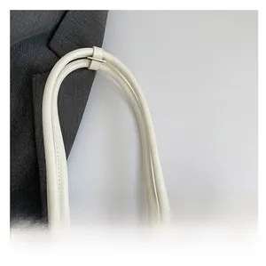 Close-up of padded leather handle on cream shoulder bag with reinforced stitching details