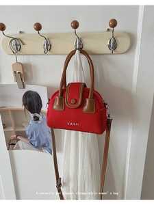 Detail of red canvas tote bag with brown leather handles hanging on a wooden hook