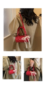 Detailed view of a red polka dot cylindrical handbag with lace and pearl bow accents