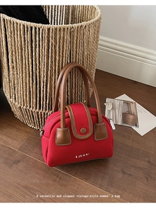 Close-up of red canvas handbag with brown leather handles and LIVUU logo on wooden floor