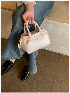Detail of light pink pebbled leather tote with drawstring accents and fashion text