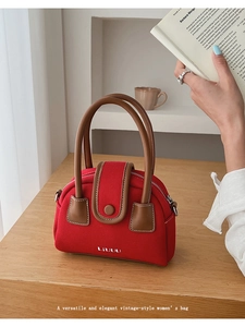 Detail of red canvas bowling bag with brown leather handles on a wooden table