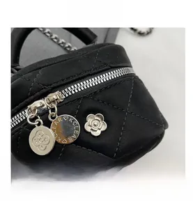 Détail du mini sac matelassé noir avec camélia argenté et pendentifs logo