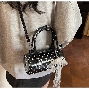 Close-up of a polka dot Boston bag featuring a pearl lace bow and thin crossbody strap