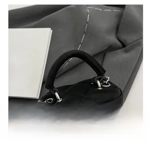 Détail d'un sac à main matelassé en nylon noir avec chaîne argentée et double fermeture