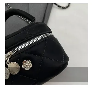 Détail de fermeture éclair argentée et pendentif camélia sur sac matelassé noir