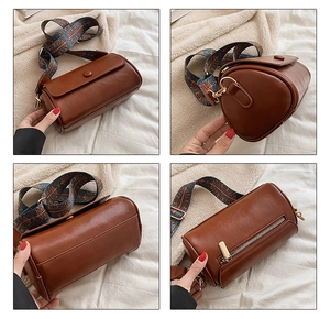 Detailed view of brown cylinder bag with ethnic patterned wide strap and gold hardware