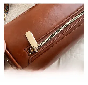 Close-up of caramel brown cylinder bag featuring leather texture and gold hardware details