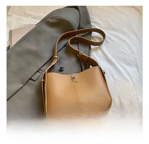 Detail of tan lychee pattern leather bucket bag featuring a metal turn-lock closure