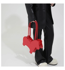 Detail of red dog-shaped animal purse paired with a black leather suit for a bold look