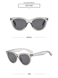 Detail view of gray transparent cat eye sunglasses with metal rivet accents and dark lenses