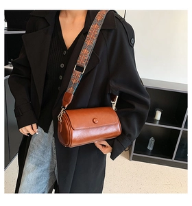 Brown vintage cylinder crossbody bag featuring a colorful wide woven shoulder strap