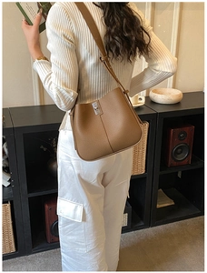 Rear view of brown lychee leather bucket bag with silver turn-lock on white outfit
