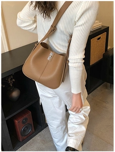 Detailed view of caramel leather bucket bag with silver lock and pebble grain texture